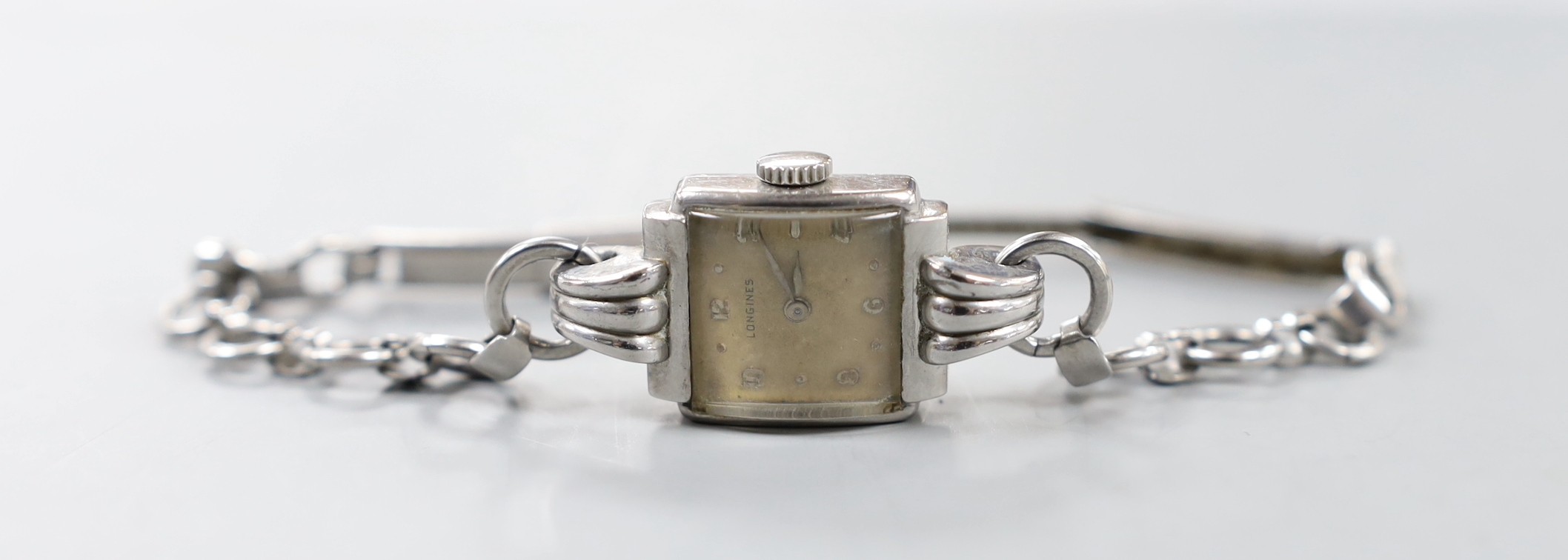 A lady's stainless steel Longines manual wind wrist watch, with fluted lugs, on associated steel chain link bracelet.